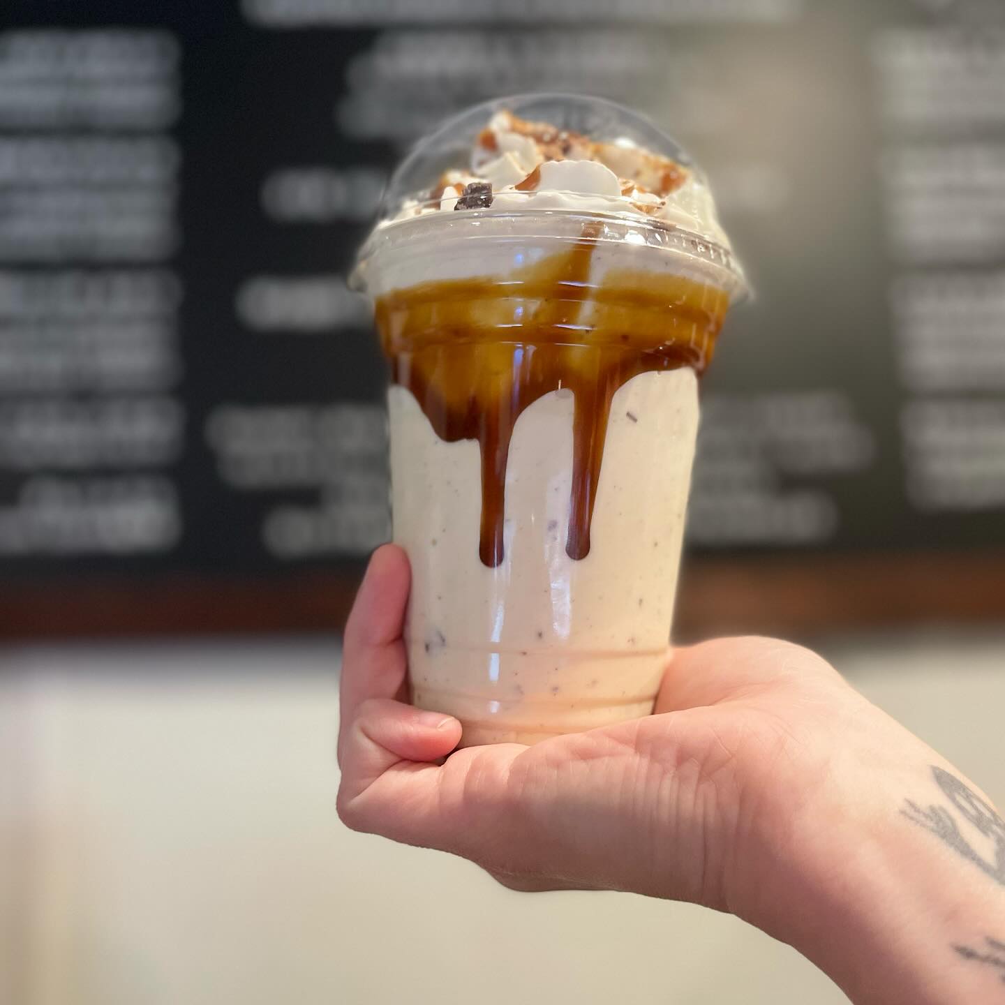 Hand-held custom milkshake drizzled with chocolate