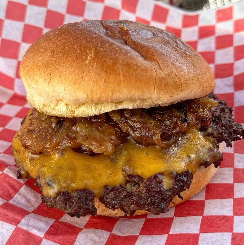 Double smash burger with cheddar and caramelized onions on a red-checker basket