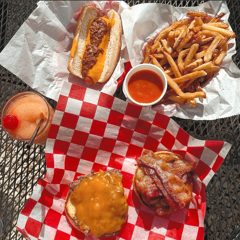 Burgers, fries, and a hot dog on Peanut Gallery’s red checkered paper